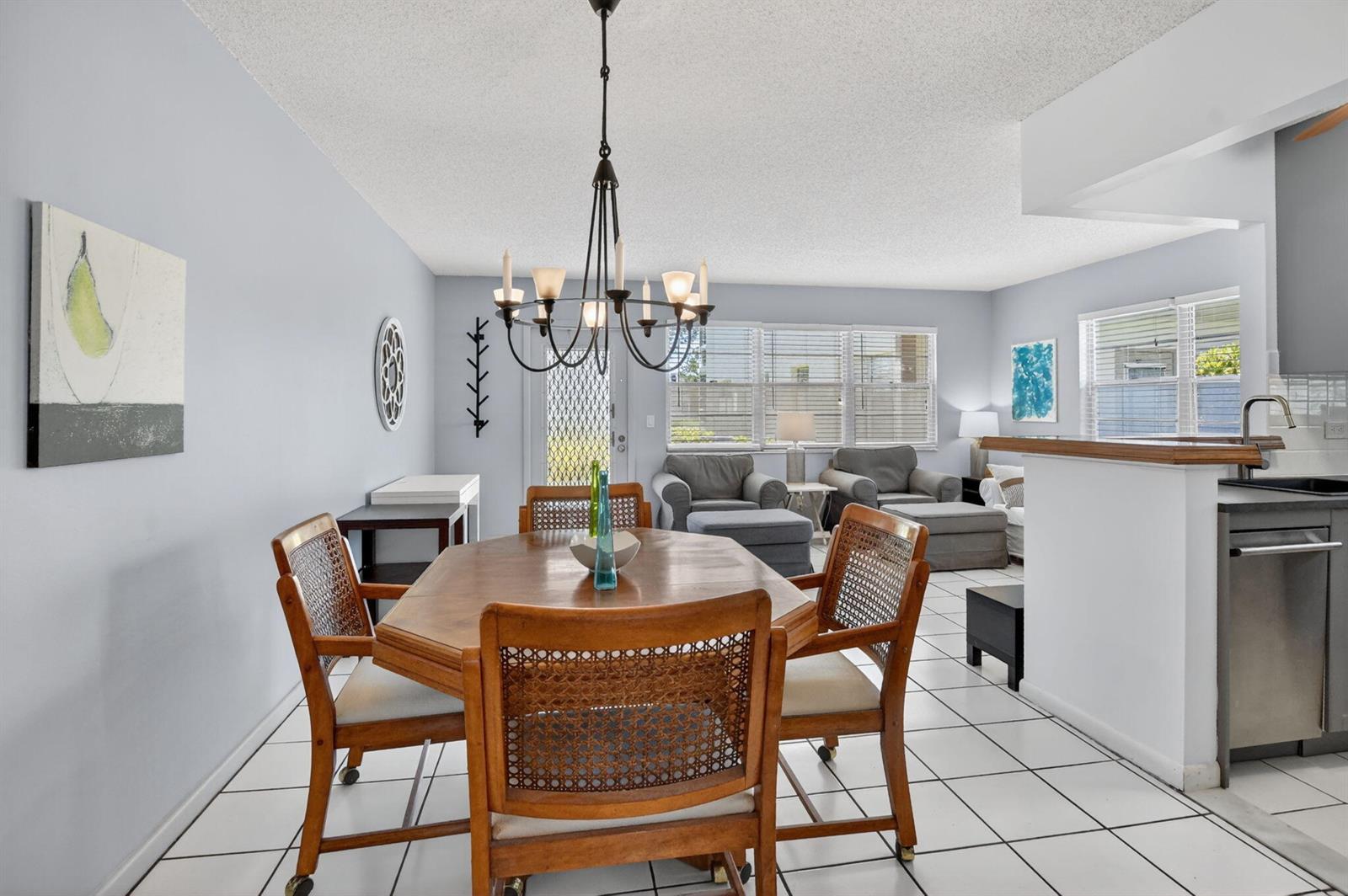 A dining area with a wooden table and chairs sits adjacent to a kitchen and living room — 492 W Tilford, Deerfield Beach FL 33442, DEERFIELD BEACH, FL