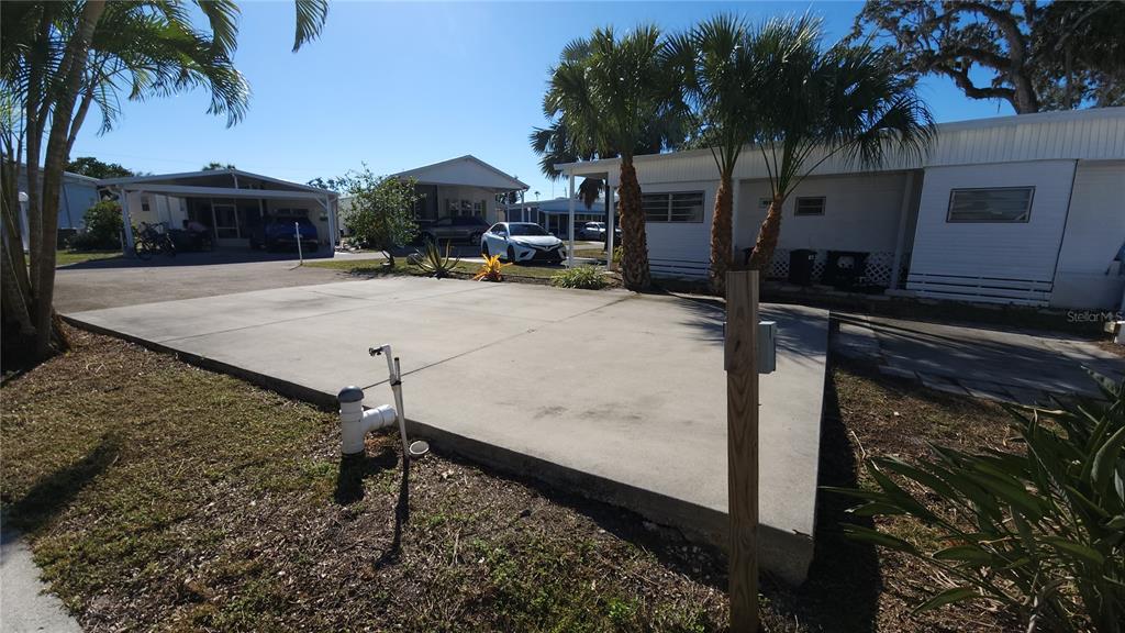A concrete pad sits in front of a mobile home with palm trees nearby — 3275 26TH AVENUE E UNIT 165, BRADENTON, FL
