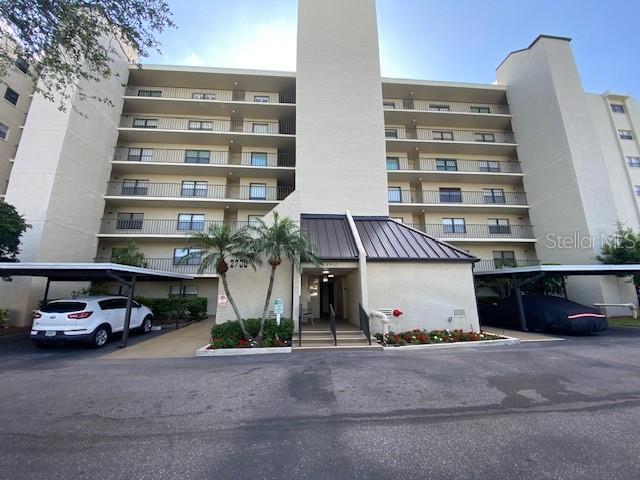 A multi-story apartment building features covered parking spaces and a central entrance — 2700 COVE CAY DRIVE UNIT 1-6D, CLEARWATER, FL