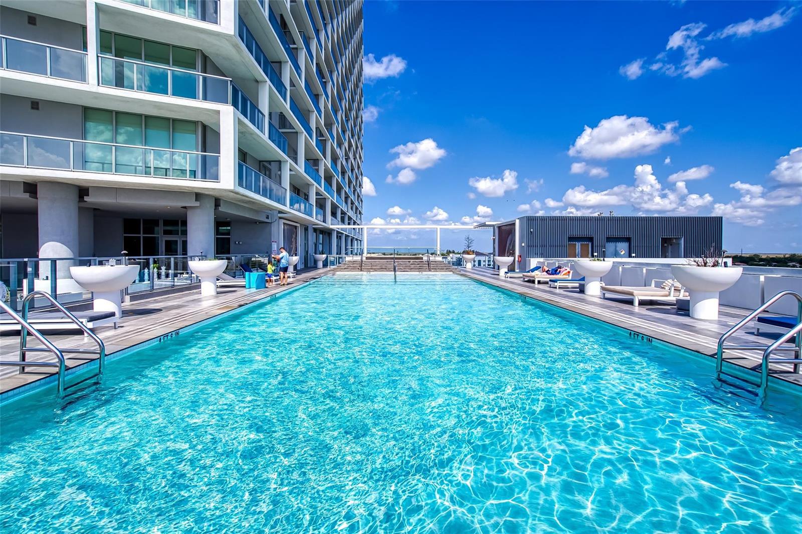 A modern high-rise apartment building features a long outdoor swimming pool on a rooftop deck — 2000 Metropica Way # 1410, Sunrise FL 33323, SUNRISE, FL