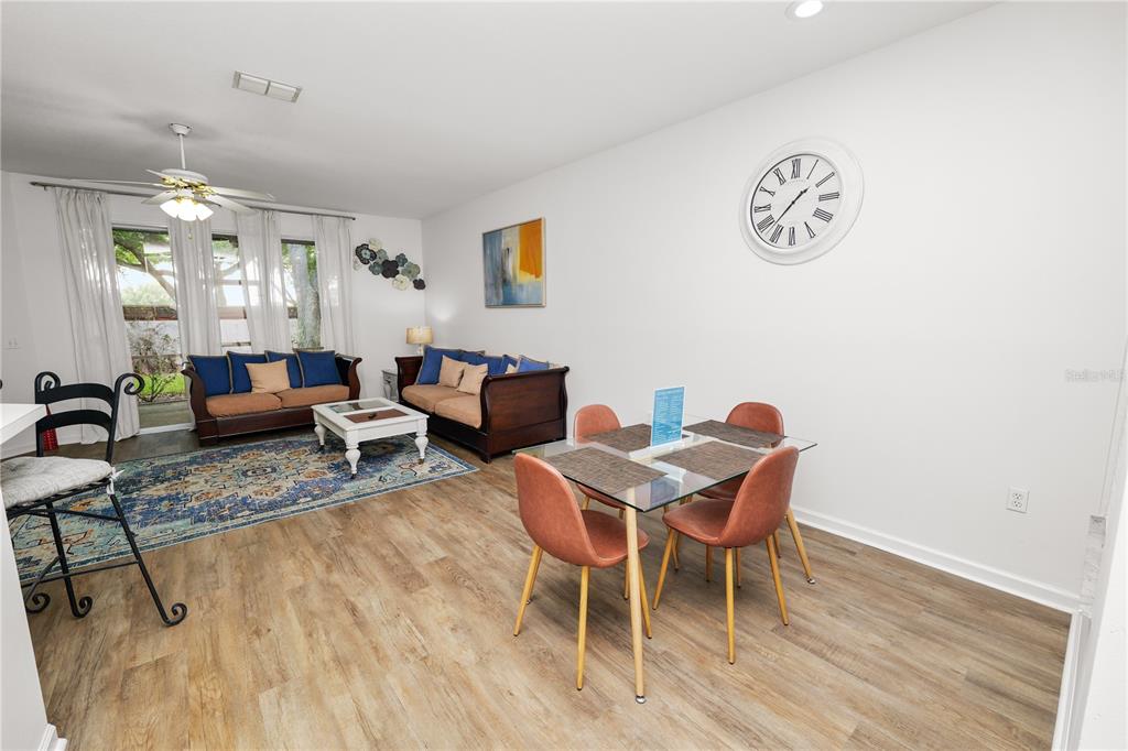A living and dining area with wood-look flooring, a glass table, and two sofas — 774 GRASSLANDS VILLAGE CIRCLE UNIT 88, LAKELAND, FL