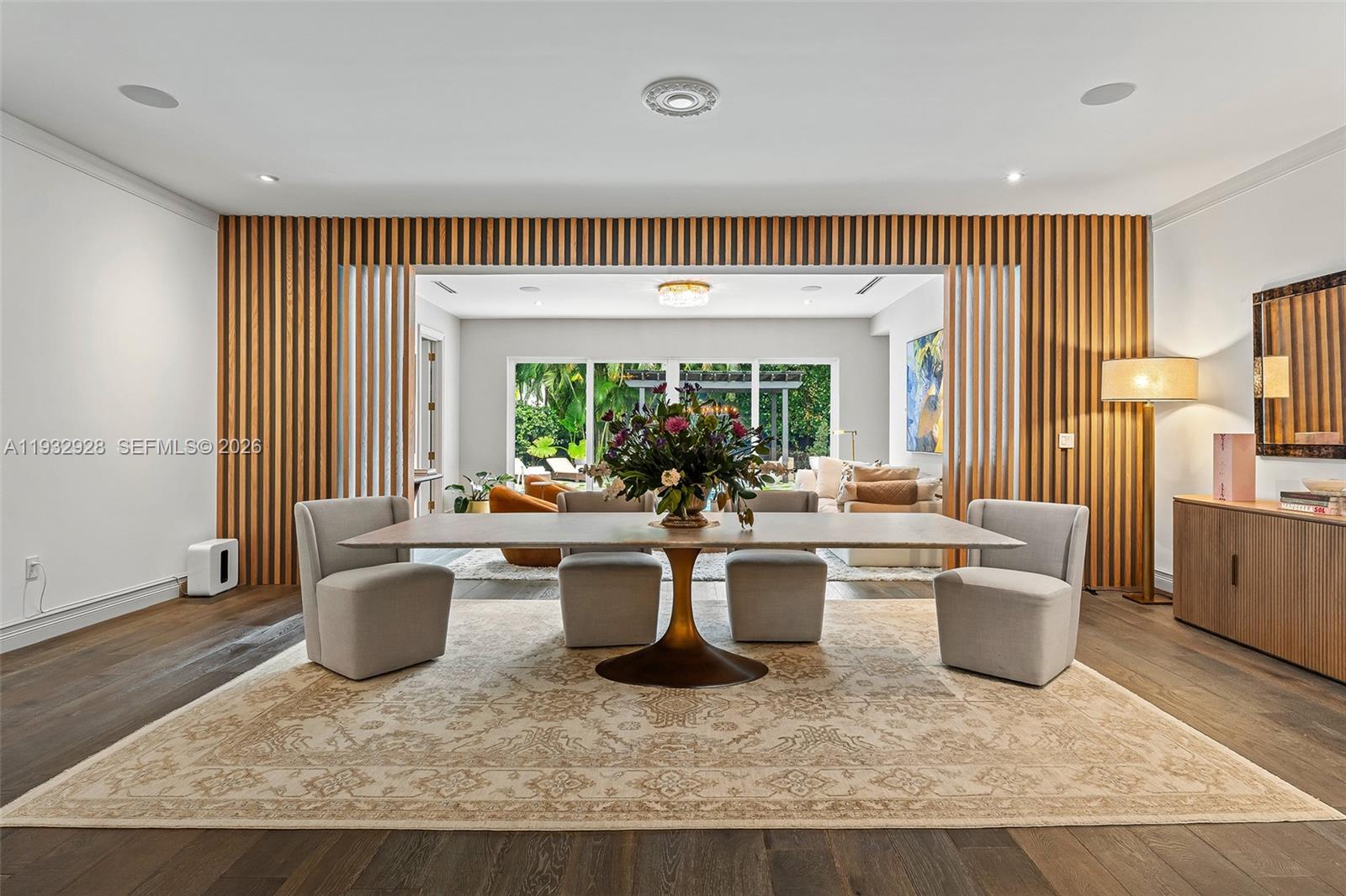 A dining room features a long table, upholstered chairs, and a wood-slatted accent wall — 680 Buttonwood Ln, Miami FL 33137, MIAMI, FL