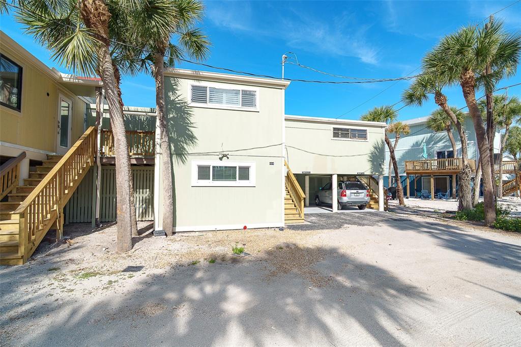 An exterior view of a two-story light green house with elevated decks and palm trees — 2980 N BEACH ROAD UNIT C2-4, ENGLEWOOD, FL
