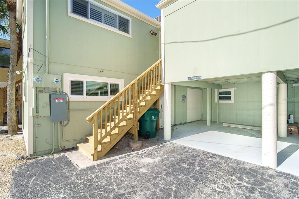 An exterior view of a light green house with wooden stairs and a covered carport — 2980 N BEACH ROAD UNIT C2-4, ENGLEWOOD, FL