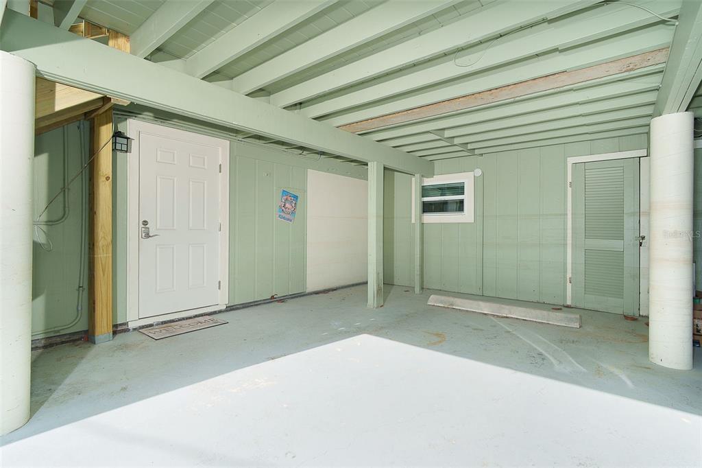 A covered ground-level patio area features light green siding, two doors, and structural support columns — 2980 N BEACH ROAD UNIT C2-4, ENGLEWOOD, FL