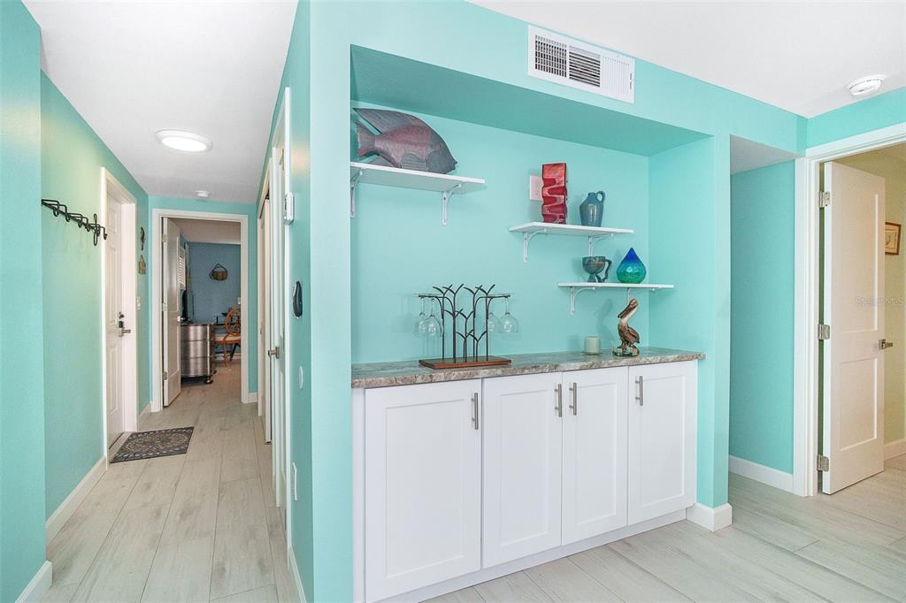 A hallway with light blue walls features a built-in white cabinet with open shelving above — 2980 N BEACH ROAD UNIT C2-4, ENGLEWOOD, FL