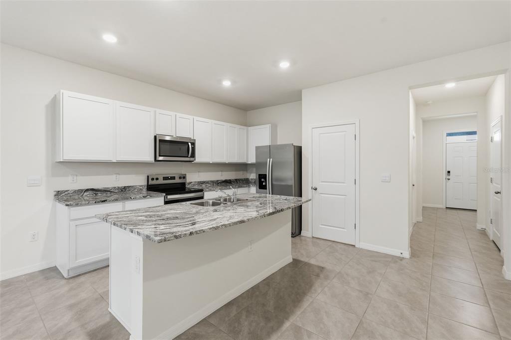 A kitchen with white cabinets, granite countertops, a center island, and stainless steel appliances — 5005 GILDED BARD COURT, WIMAUMA, FL