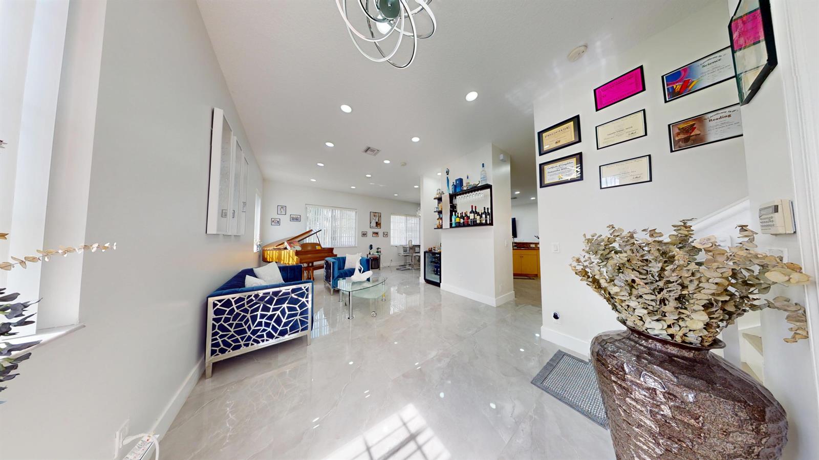 A bright living room features blue velvet sofas, a grand piano, and polished tile flooring — 8586 White Cay, West Palm Beach FL 33411, WEST PALM BEACH, FL