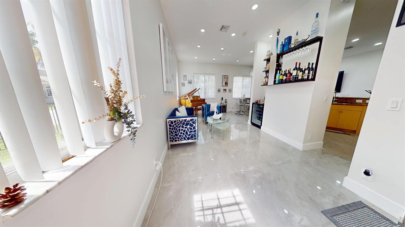 A living room features blue patterned armchairs, a grand piano, and a built-in bar area — 8586 White Cay, West Palm Beach FL 33411, WEST PALM BEACH, FL
