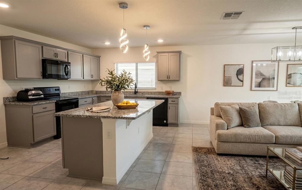 A kitchen with gray cabinets and granite countertops features a central island and pendant lighting — 1842 GOLD CREST DRIVE, ST CLOUD, FL