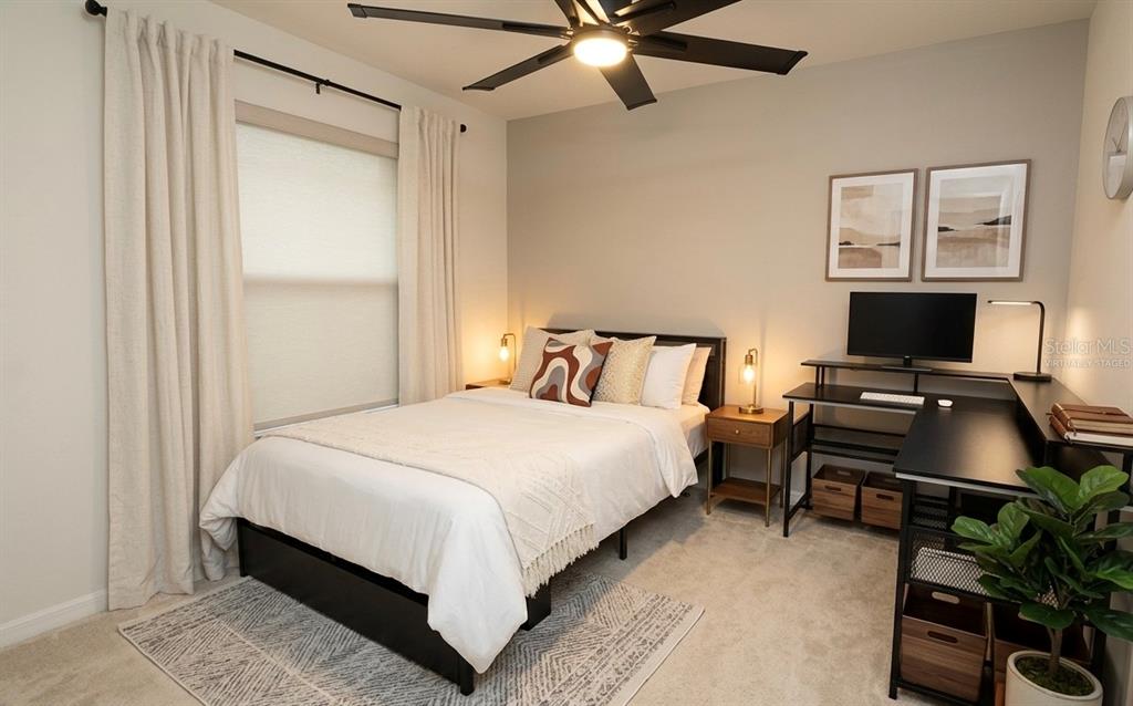 A bedroom features a bed, a desk, a ceiling fan, and a window with curtains — 1842 GOLD CREST DRIVE, ST CLOUD, FL
