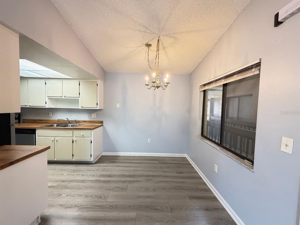 A dining area with wood-look flooring, a chandelier, and an adjacent kitchen with white cabinets — 5239 VINELAND ROAD UNIT A203, ORLANDO, FL