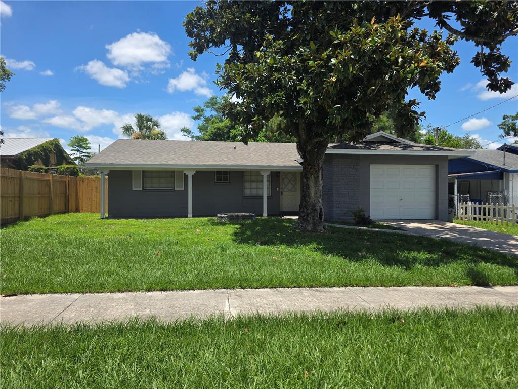 A single-story gray house with a front porch, a garage, and a large tree — 7334 PONDEROSA DRIVE, TAMPA, FL