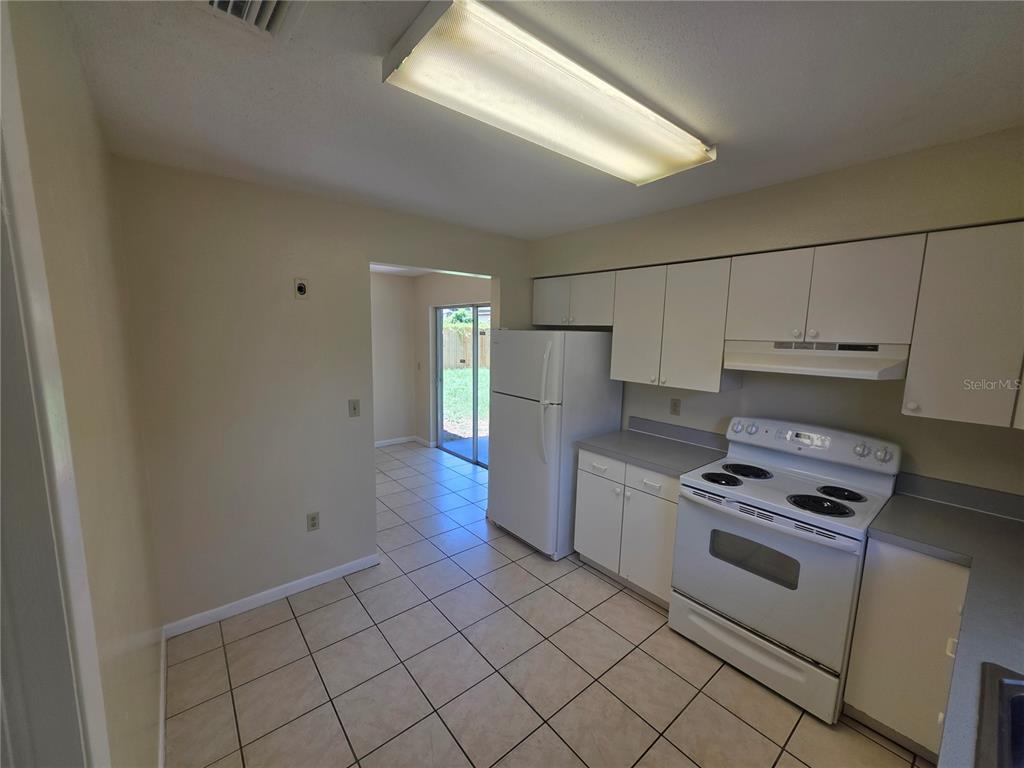 A kitchen with white cabinets, white appliances, and light-colored tile flooring — 7334 PONDEROSA DRIVE, TAMPA, FL