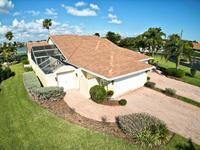 An aerial view of a single-story house with a screened-in pool and paved driveway — 204 River Walk, Fort Pierce FL 34949, FORT PIERCE, FL