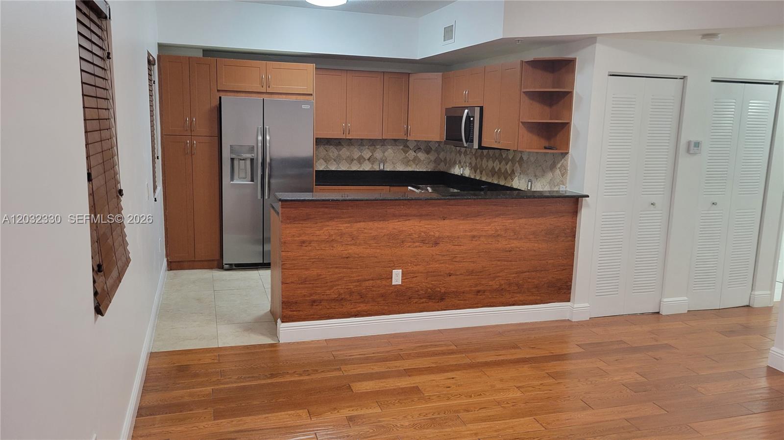 A kitchen features wood cabinets, stainless steel appliances, a breakfast bar, and tile flooring — 8430 SW 8th St # 307B, Miami FL 33144, MIAMI, FL