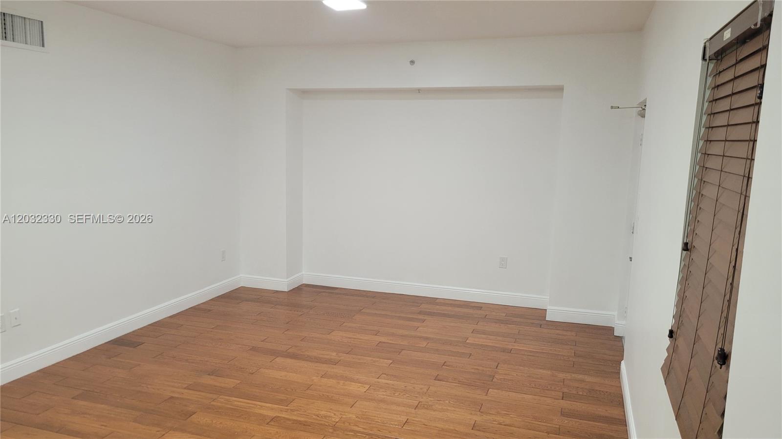 An empty room features white walls, wood-look flooring, and a recessed wall section — 8430 SW 8th St # 307B, Miami FL 33144, MIAMI, FL