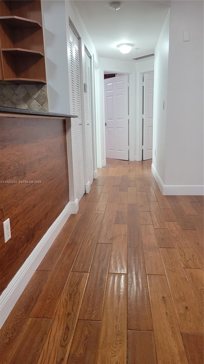 A hallway with wood-look flooring leads past louvered closet doors toward two interior white doors — 8430 SW 8th St # 307B, Miami FL 33144, MIAMI, FL