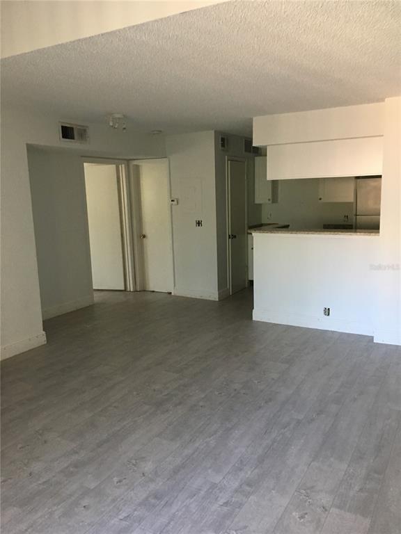 An open-concept living area features light gray wood-look flooring and a kitchen with white cabinets — 375 LAKE ONTARIO COURT UNIT 301, ALTAMONTE SPRINGS, FL