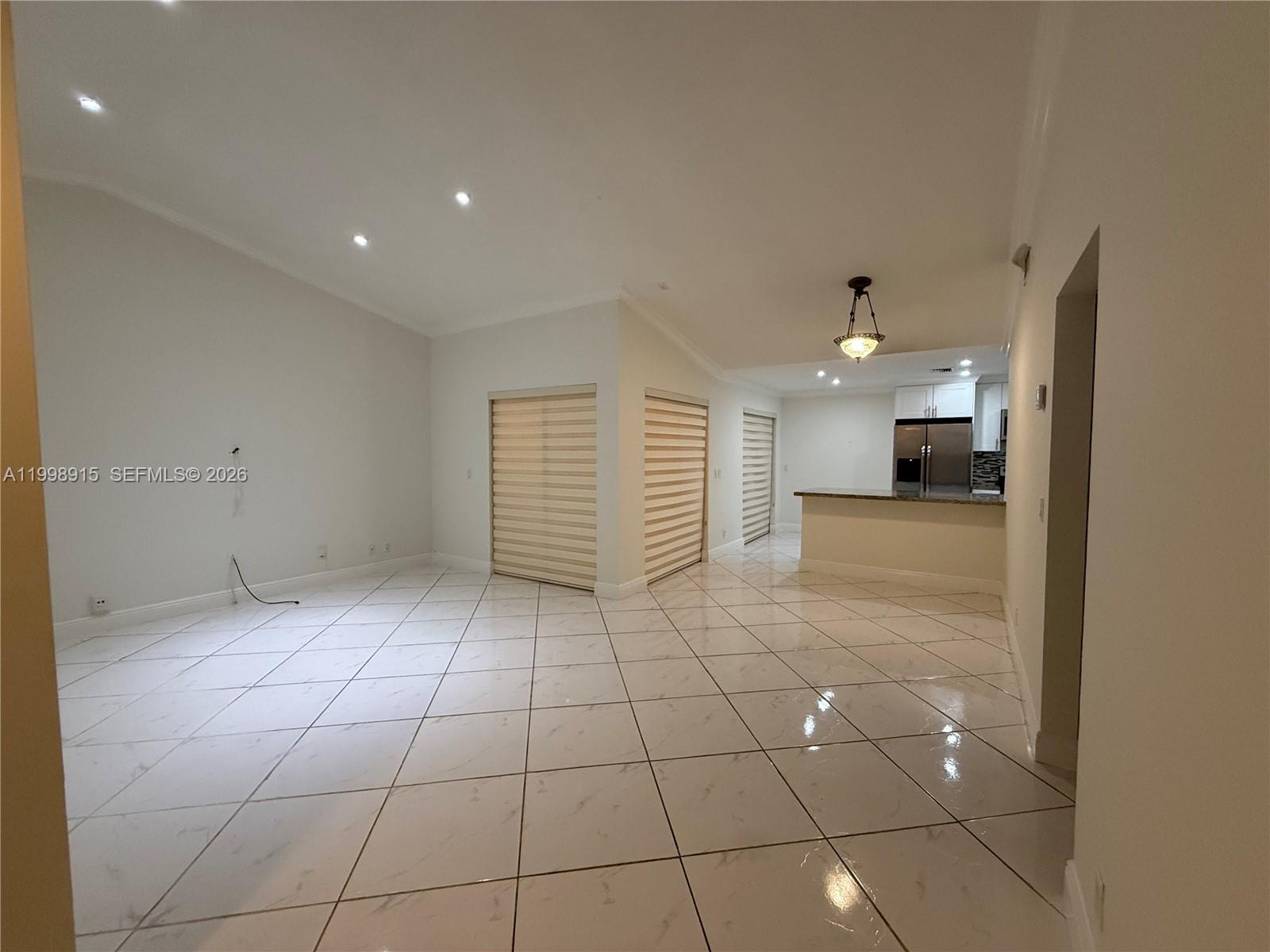 A bright, open-concept living area features white tiled floors, recessed lighting, and a kitchen — 17268 NW 60th Ct, Hialeah FL 33015, HIALEAH, FL