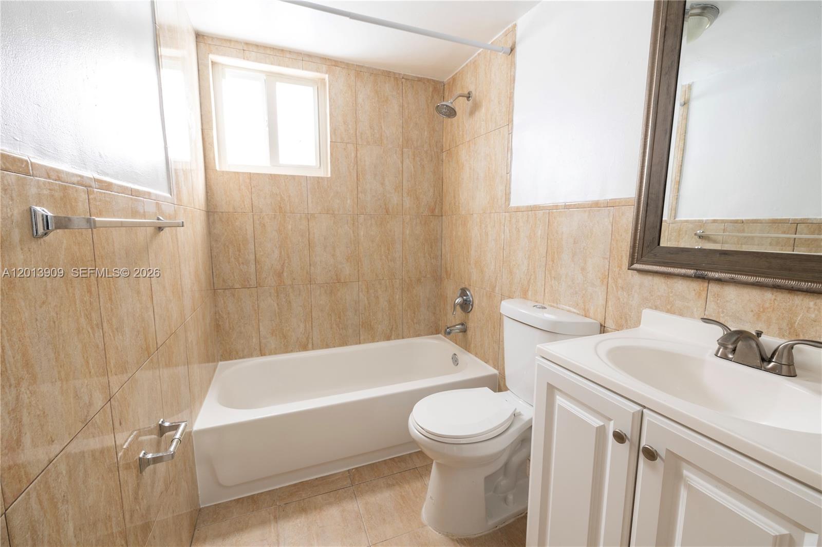 A bathroom features a white bathtub, a toilet, a vanity, and tan tiled walls — 1091 SW 4th St # 1, Miami FL 33130, MIAMI, FL