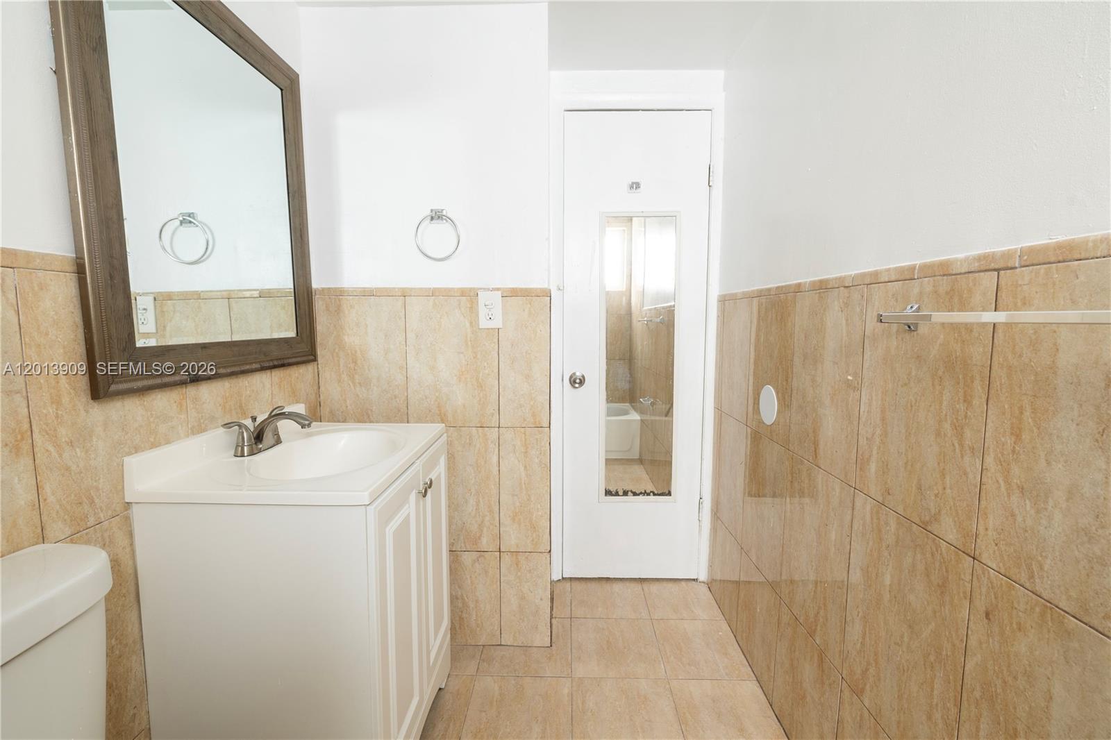 A bathroom features a white vanity, a framed mirror, and tan tiled walls — 1091 SW 4th St # 1, Miami FL 33130, MIAMI, FL