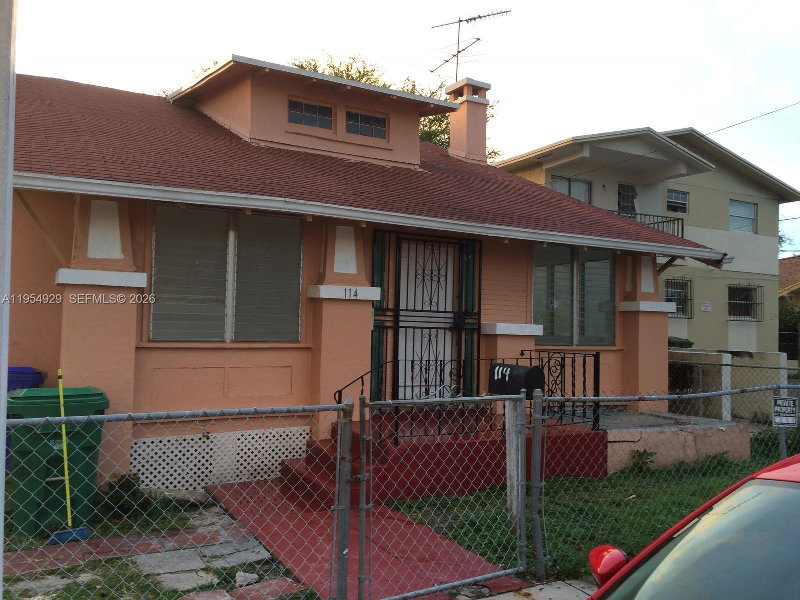 A peach-colored single-story house with a red roof and a chain-link fence — 114 NW 10th Ave, Miami FL 33128, MIAMI, FL