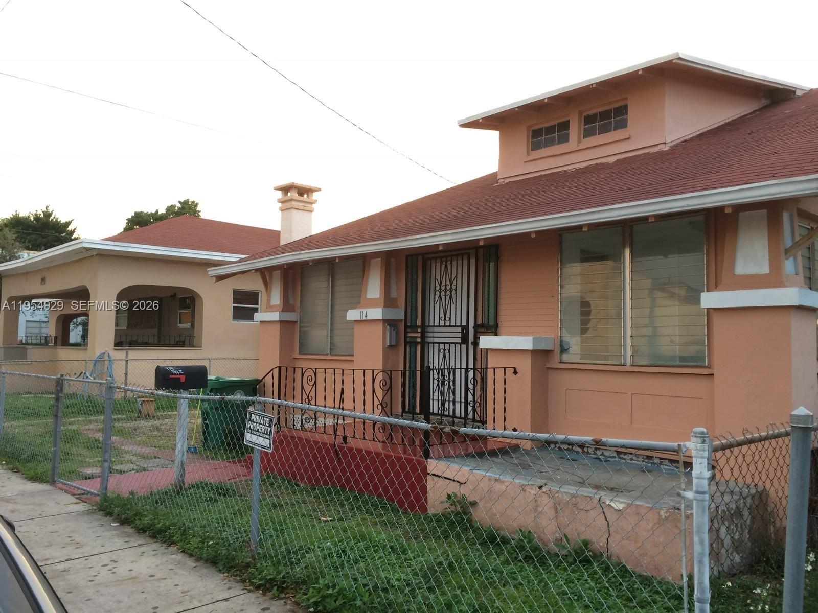 A peach-colored house with a red roof and a chain-link fence in the front yard — 114 NW 10th Ave, Miami FL 33128, MIAMI, FL