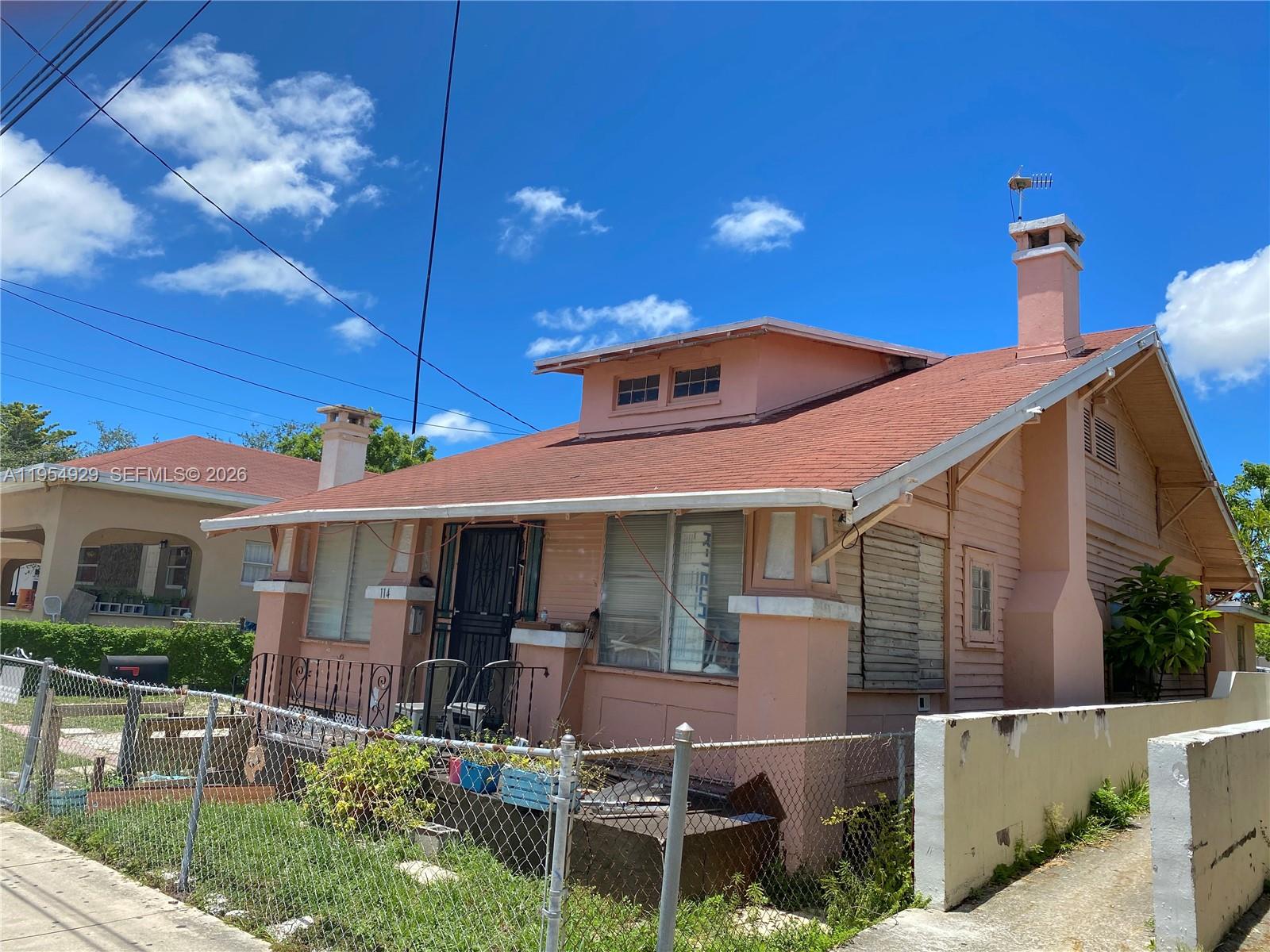 A pink, single-story house with a red roof and a chain-link fence in front — 114 NW 10th Ave, Miami FL 33128, MIAMI, FL