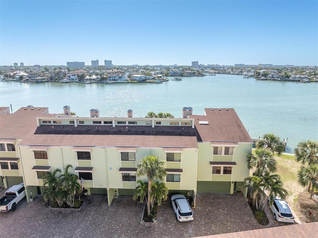 An aerial view of a multi-story townhouse complex situated along a waterfront with parked cars — 553 HAVEN POINT DRIVE, TREASURE ISLAND, FL