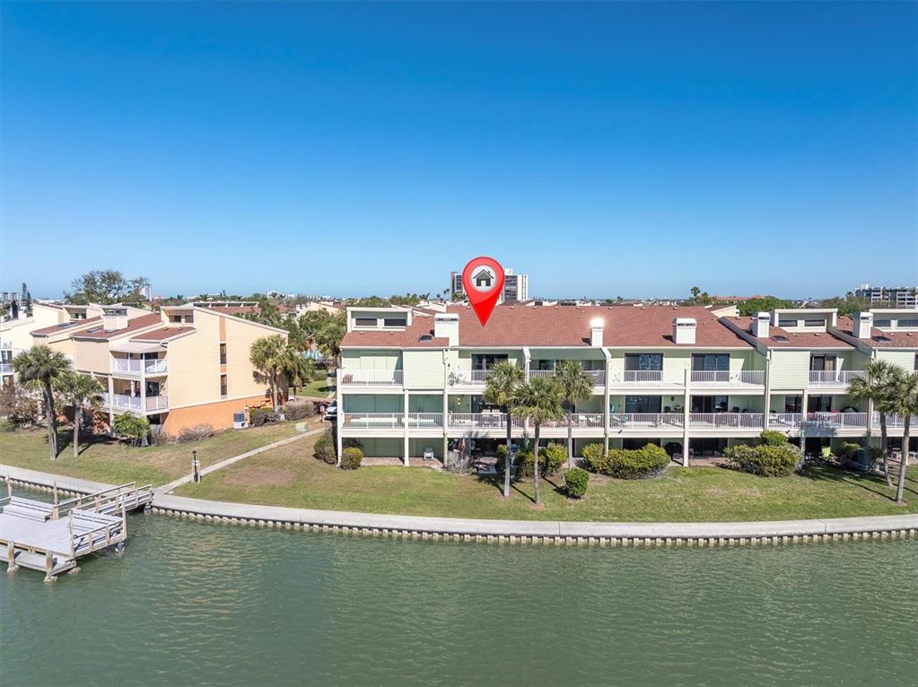 An exterior view of a multi-story waterfront condominium building with balconies and a wooden dock — 553 HAVEN POINT DRIVE, TREASURE ISLAND, FL
