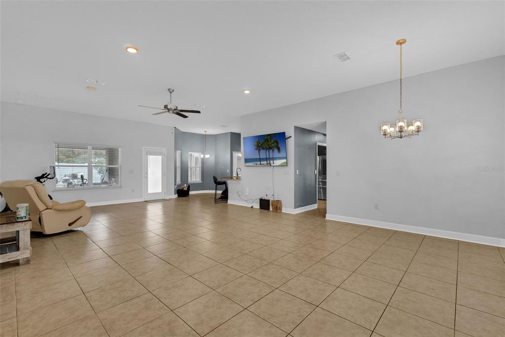 An open-concept living and dining area features tile flooring, a ceiling fan, and a television — 15 ZELDA COURT, PALM COAST, FL