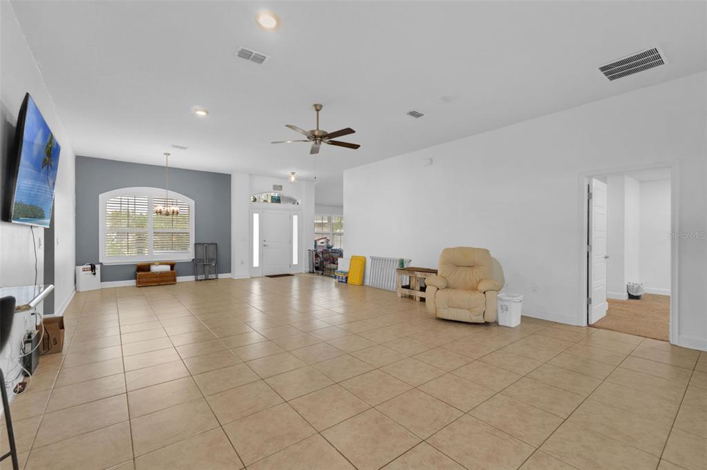A spacious living room features light tile flooring, white walls, a ceiling fan, and arched windows — 15 ZELDA COURT, PALM COAST, FL