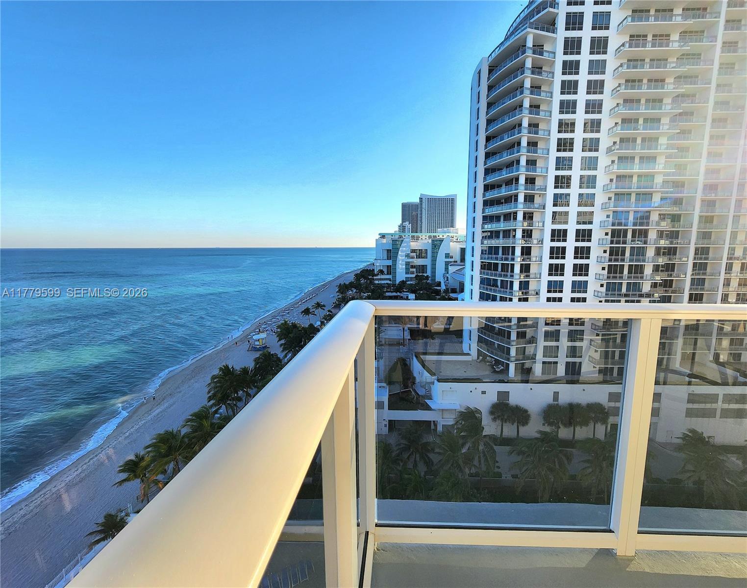 A balcony view overlooks a sandy beach, the ocean, and a tall residential building — 3505 S Ocean Dr # 1214, Hollywood FL 33019, HOLLYWOOD, FL