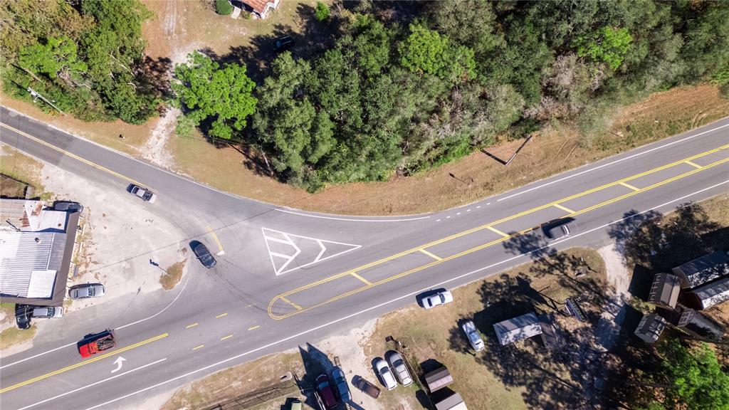 An aerial view shows a rural road intersection with a triangular traffic island and buildings — 815 NE 145TH AVENUE ROAD, SILVER SPRINGS, FL