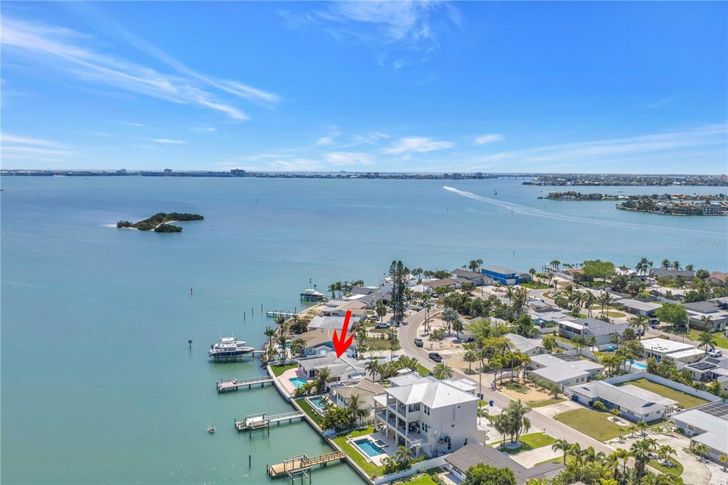 An aerial view shows a waterfront house with a pool and dock on the bay — 6984 S SHORE DRIVE S, ST PETERSBURG, FL
