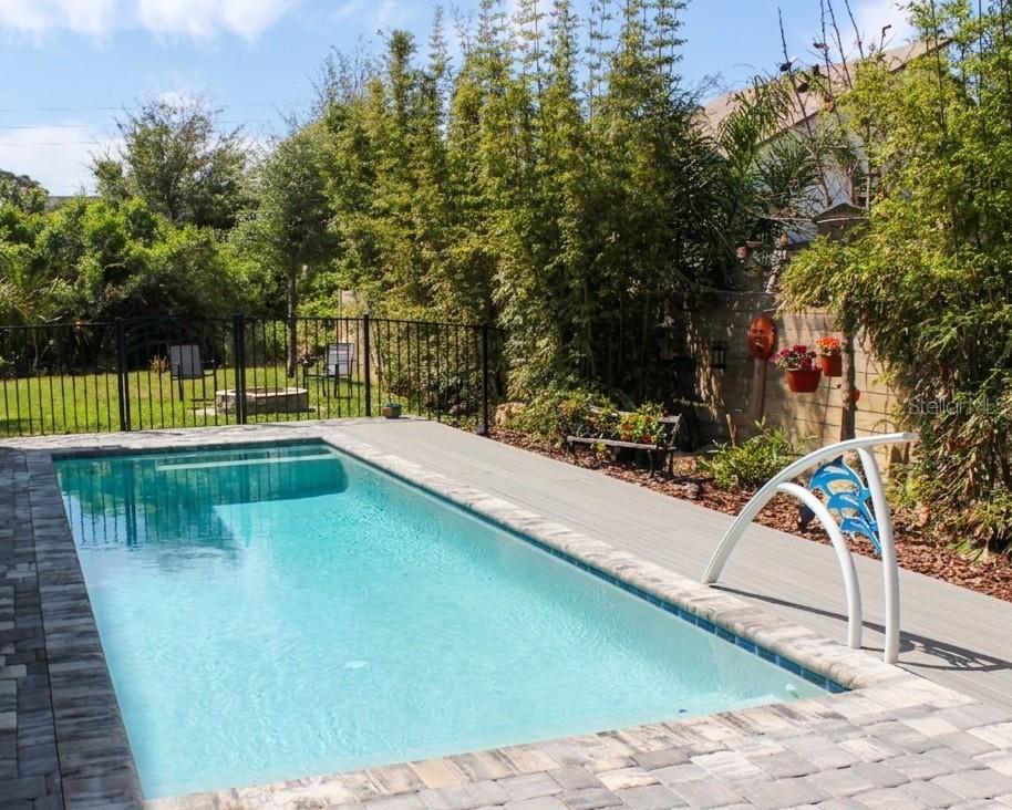 A rectangular swimming pool with a gray deck and stone pavers sits in a backyard — 4 ULMACEA PLACE, PALM COAST, FL