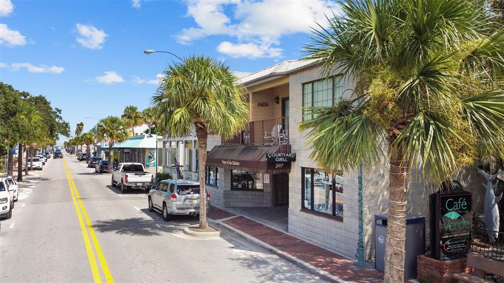 A street view shows a two-story building with a restaurant, palm trees, and parked cars — 307 FLAGLER AVENUE UNIT 101, NEW SMYRNA BEACH, FL