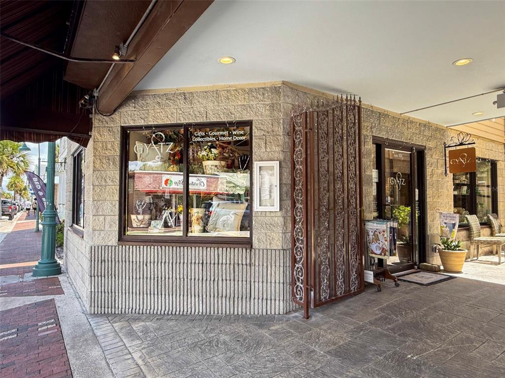 The exterior of a retail storefront features stone walls, a large display window, and signage — 307 FLAGLER AVENUE UNIT 101, NEW SMYRNA BEACH, FL