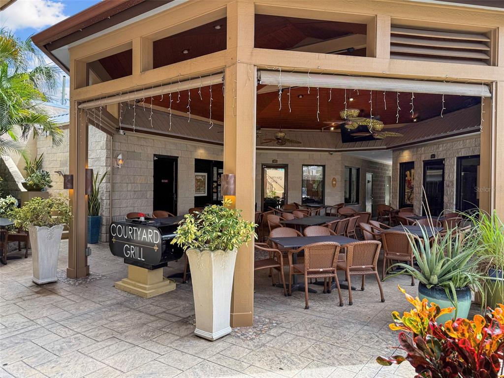 An outdoor covered patio features dining tables, wicker chairs, potted plants, and a grill station — 307 FLAGLER AVENUE UNIT 101, NEW SMYRNA BEACH, FL