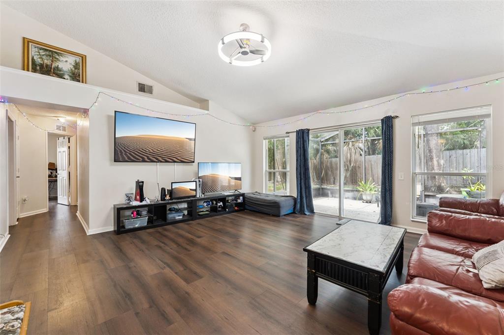 A living room features wood-look flooring, a wall-mounted television, a media console, and leather seating — 266 HANGING MOSS CIRCLE, LAKE MARY, FL