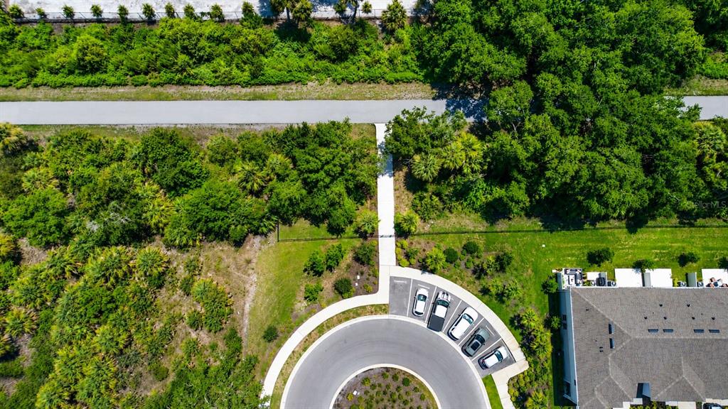 An aerial view shows a cul-de-sac with parked cars, a sidewalk, and surrounding wooded areas — 5848 BISCOTTI STREET, NOKOMIS, FL