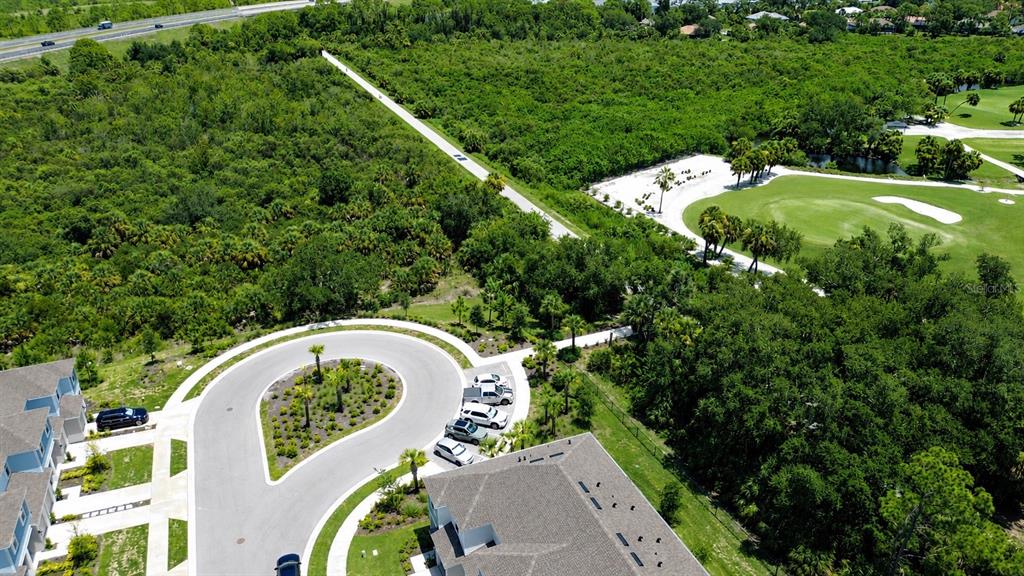 An aerial view shows a residential cul-de-sac adjacent to a golf course and dense woods — 5848 BISCOTTI STREET, NOKOMIS, FL
