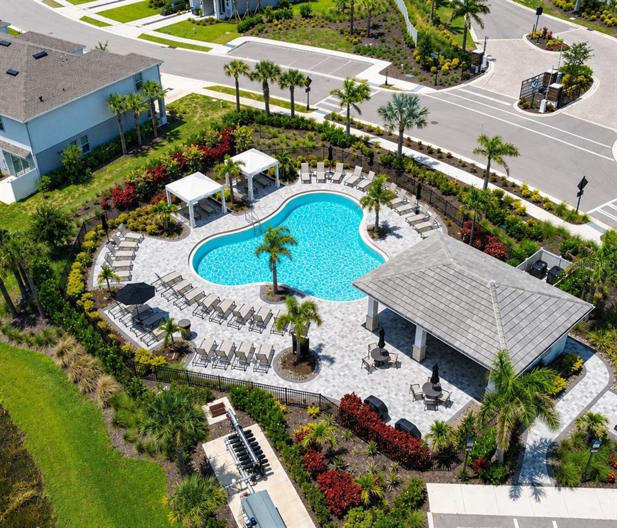 An aerial view shows a community swimming pool with lounge chairs, cabanas, and a pavilion — 5848 BISCOTTI STREET, NOKOMIS, FL