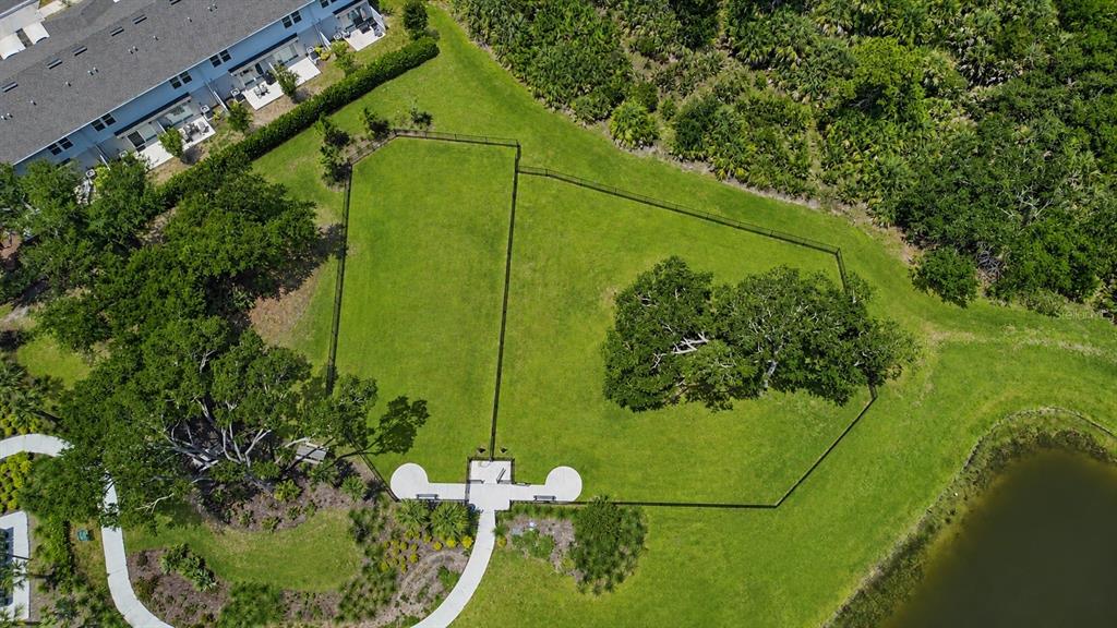 An aerial view shows a fenced-in grassy park area with large trees and a walkway — 5848 BISCOTTI STREET, NOKOMIS, FL