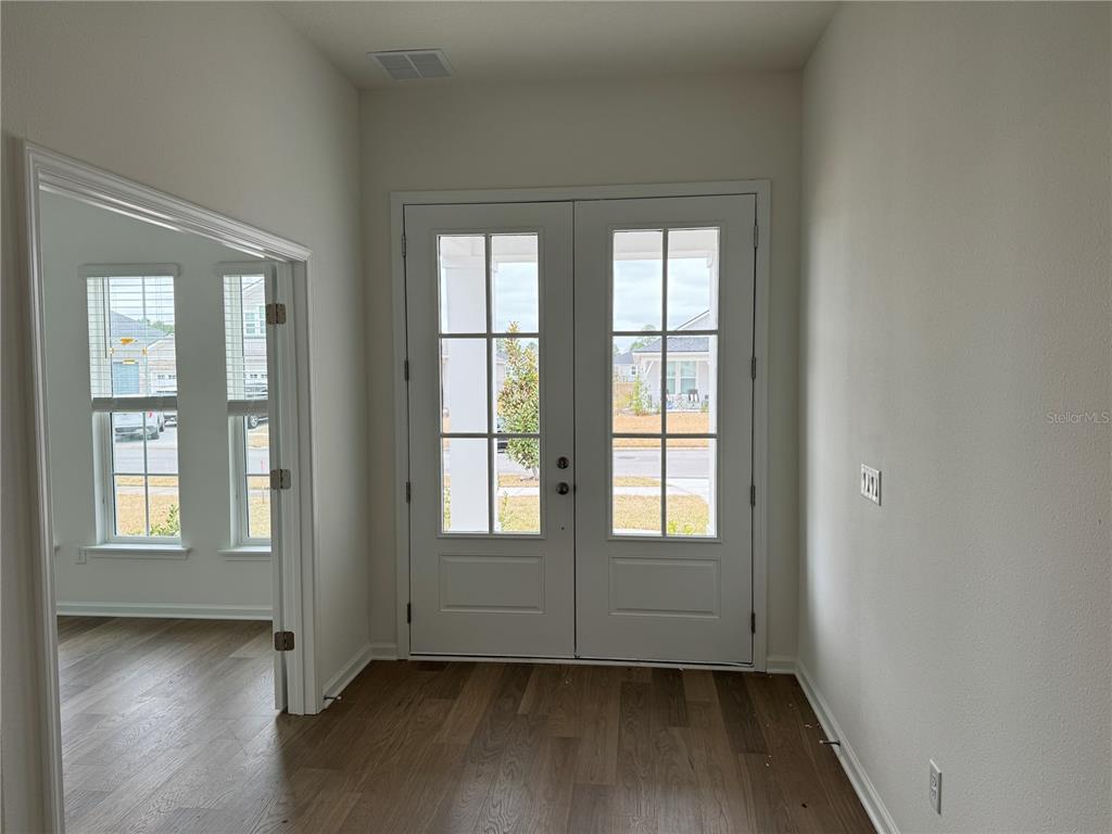 A white single-story house with a three-car garage and a dark roof under blue skies — 3581 ZYDECO LOOP, GREEN COVE SPRINGS, FL
