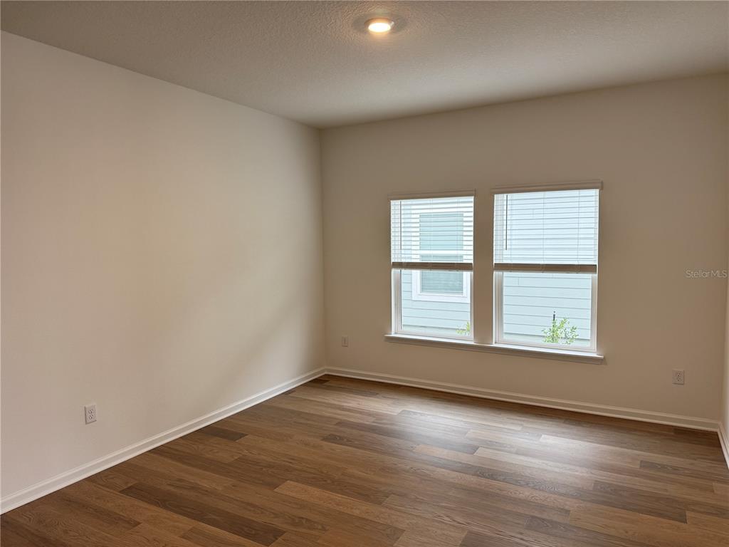 An empty room with light wood flooring, white walls, large windows, and double glass doors — 3581 ZYDECO LOOP, GREEN COVE SPRINGS, FL