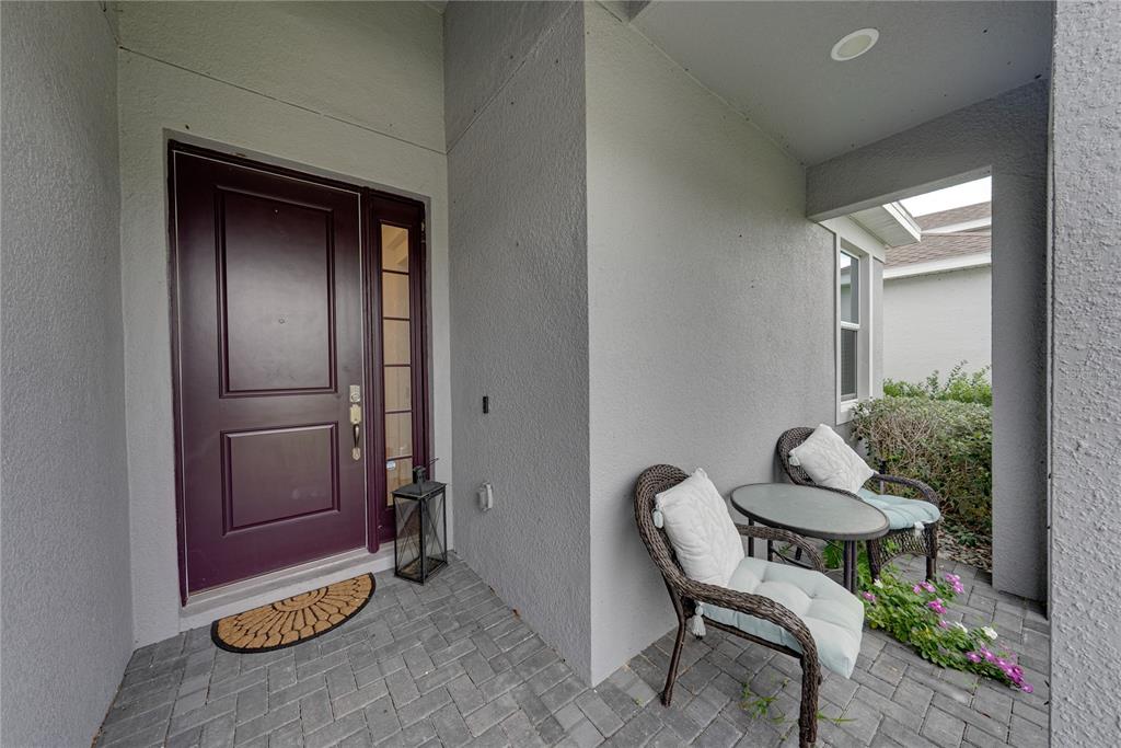 The exterior of a gray house features a paved walkway, a garage, and landscaped bushes — 2235 PIGEON PLUM DRIVE, HAINES CITY, FL