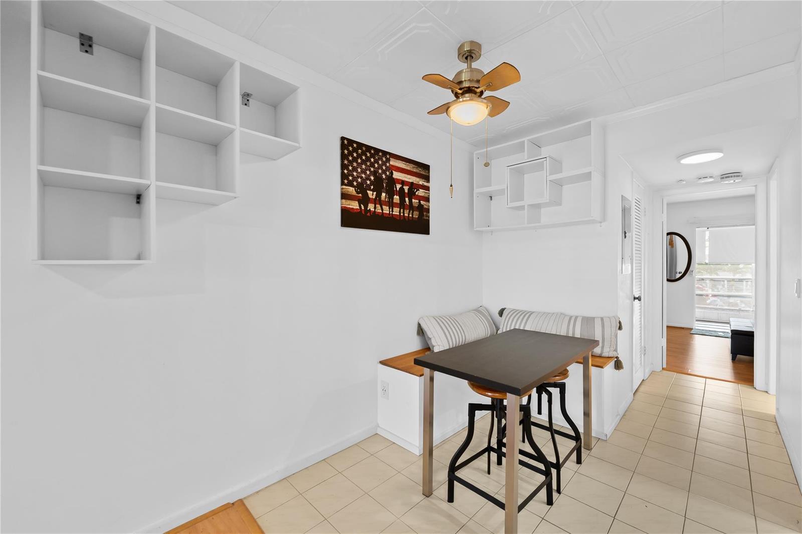 A dining area features a built-in bench, a small table, wall shelving, and tile flooring — 39 Prescott B # 39, Deerfield Beach FL 33442, DEERFIELD BEACH, FL