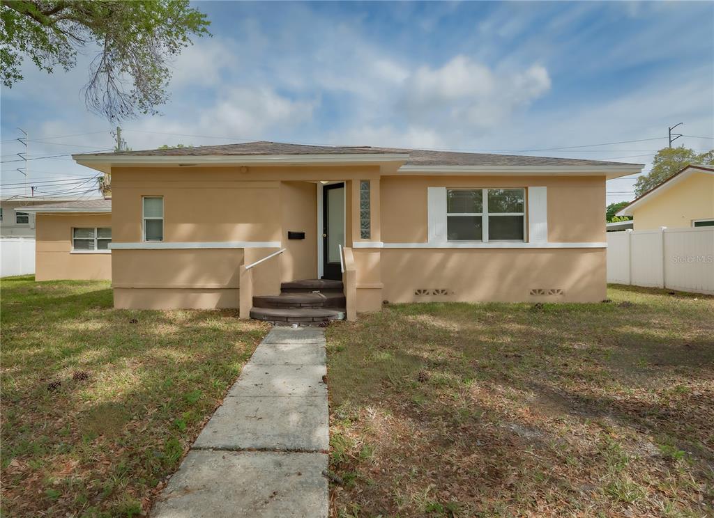 A single-story tan house with a concrete walkway leading to a recessed front entrance — 6465 1ST AVENUE S, ST PETERSBURG, FL